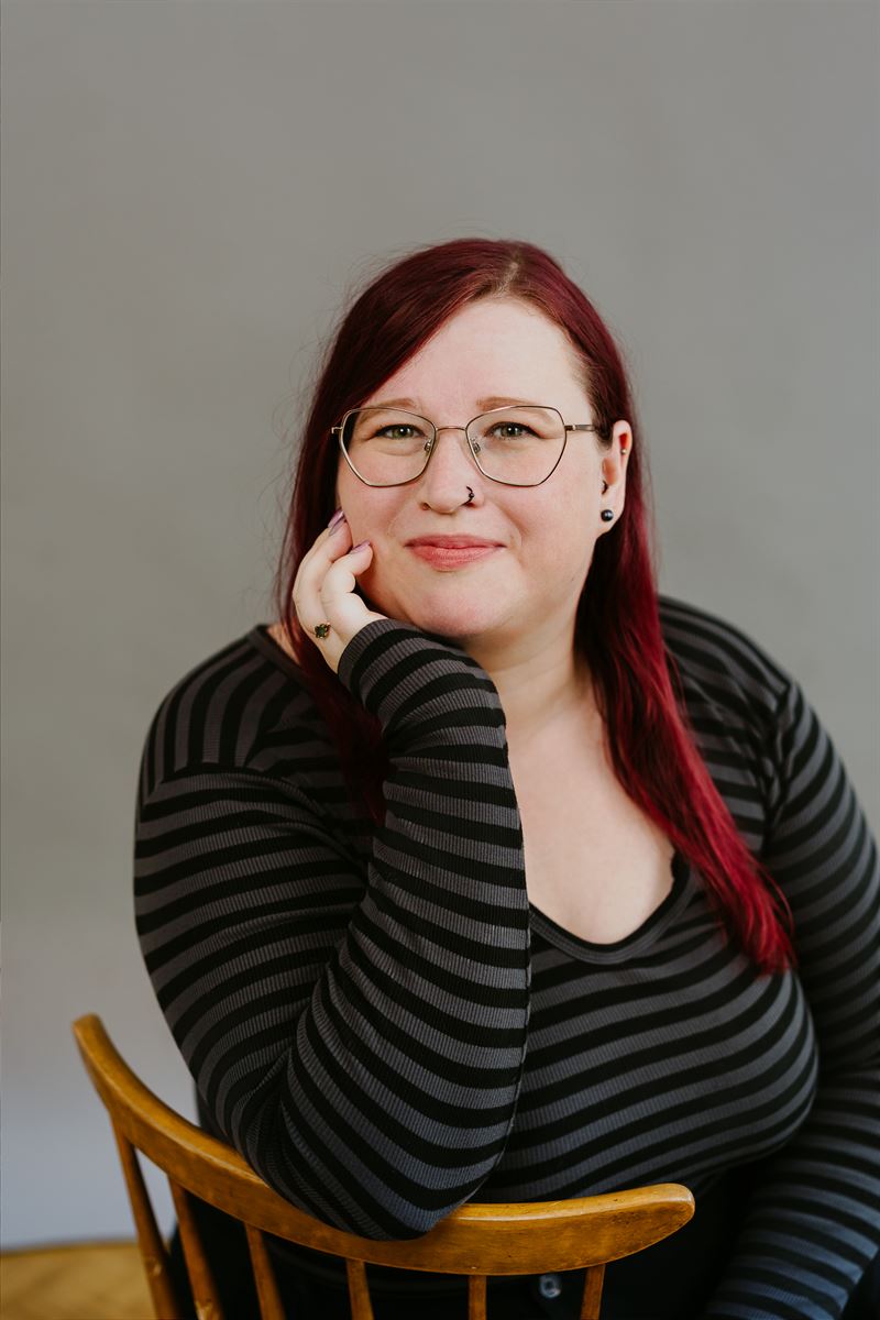 Anne-Katrin Falkensteiner sitzt lächelnd auf einem Holzstuhl